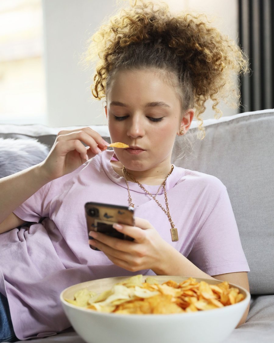A child relaxing at home with their smartphone.